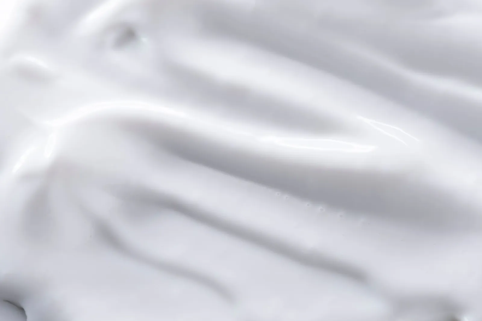 A detailed close-up of a smooth white cream texture, perfect for backgrounds or food imagery.